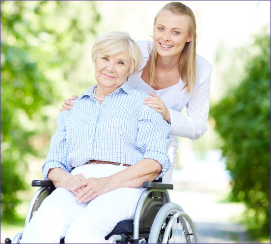 Woman in wheelchair with younger woman behind her, smiling